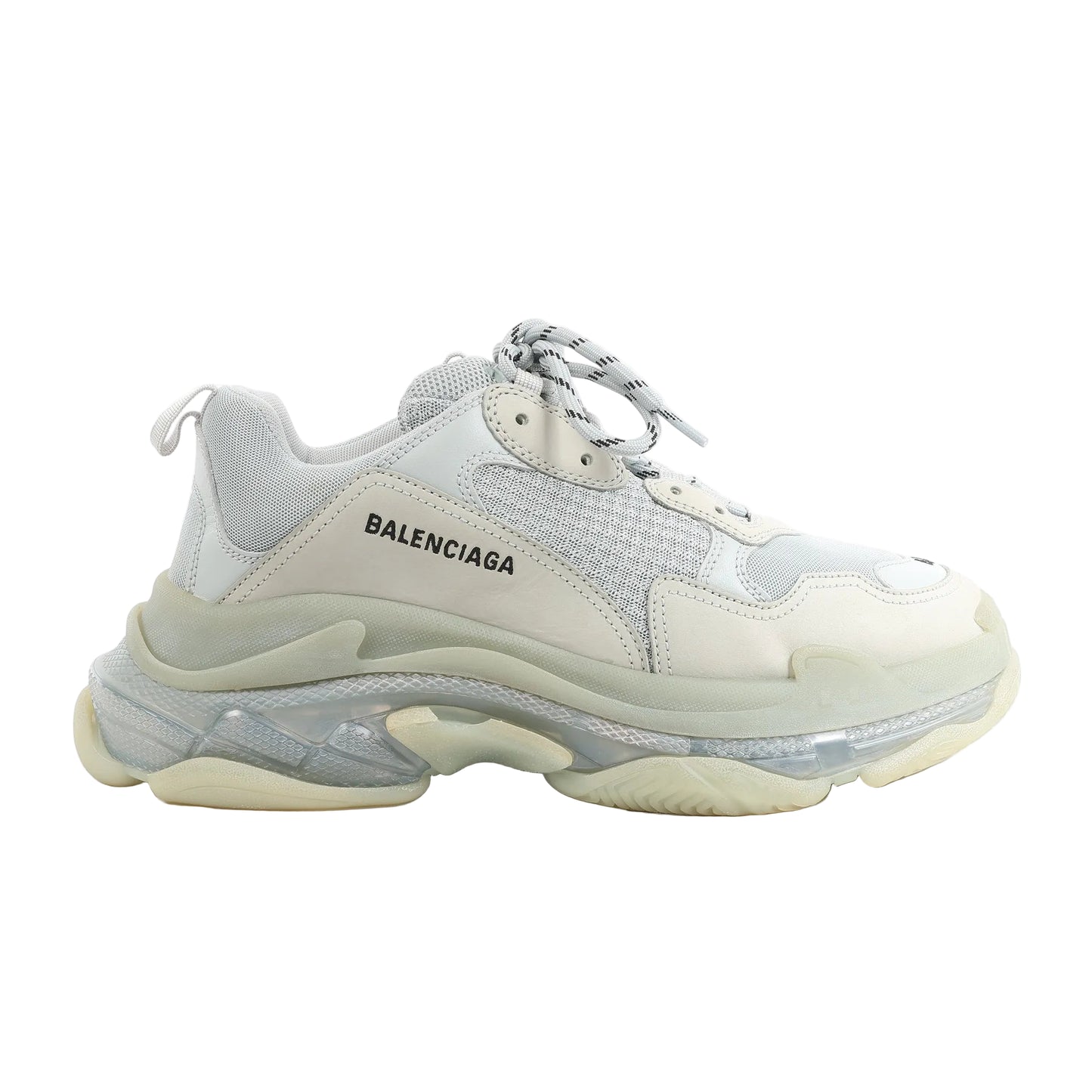 Side view of a gray Balenciaga Triple S 541624 sneaker in size 44 EU, featuring layered mesh and leather upper, thick translucent and rubber sole, and round laces with black stripes.