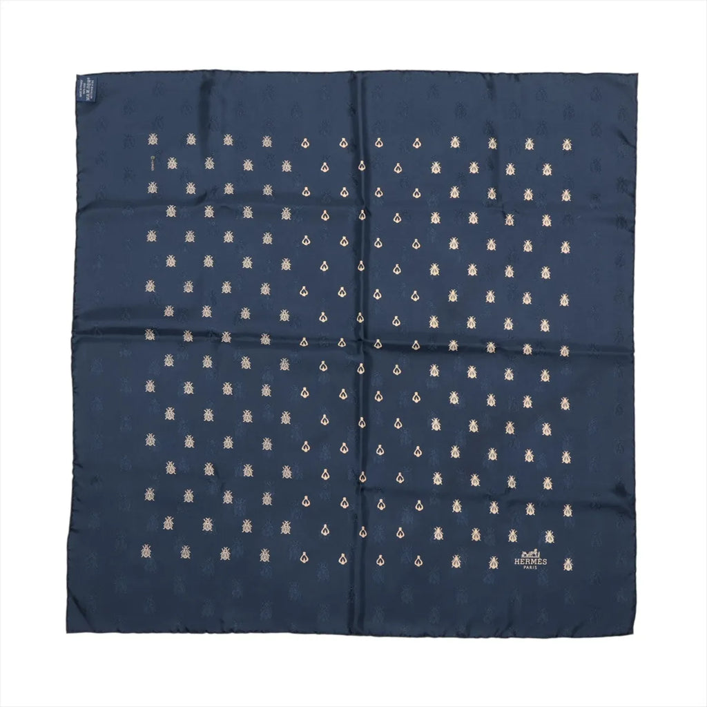 Navy blue Hermès Carré 70 silk scarf laid flat with repeating small gold-tone bee motifs and a tonal border.