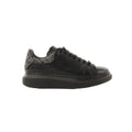 Side view of black leather Alexander McQueen platform trainer with black laces and a glitter heel tab on a white background.