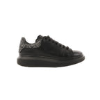 Side view of black leather Alexander McQueen platform trainer with black laces and a glitter heel tab on a white background.
