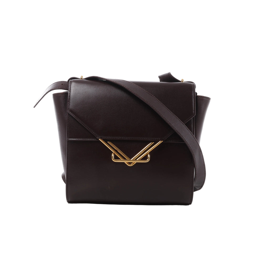Burgundy Bottega Veneta The Clip leather crossbody bag with angular flap, wide shoulder strap and sculptural gold-tone V-shaped hardware.