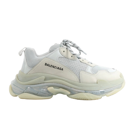 Side view of a gray Balenciaga Triple S 541624 sneaker in size 44 EU, featuring layered mesh and leather upper, thick translucent and rubber sole, and round laces with black stripes.