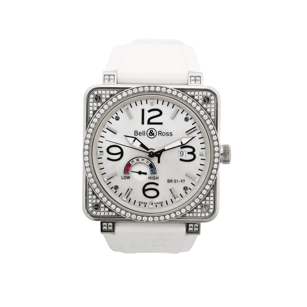 Bell & Ross square stainless steel watch with white dial, black Arabic numerals, date window, power reserve gauge, diamond-set bezel and case details, and white rubber strap.