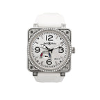 Bell & Ross square stainless steel watch with white dial, black Arabic numerals, date window, power reserve gauge, diamond-set bezel and case details, and white rubber strap.