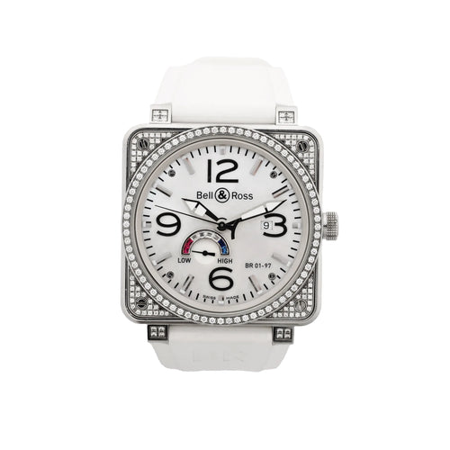 Bell & Ross square stainless steel watch with white dial, black Arabic numerals, date window, power reserve gauge, diamond-set bezel and case details, and white rubber strap.