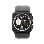 Front view of Bell & Ross BR 03-94 watch with matte black square case, black dial with white markers and large 12 and 6, orange accents, chronograph subdials, date window, and black rubber strap.