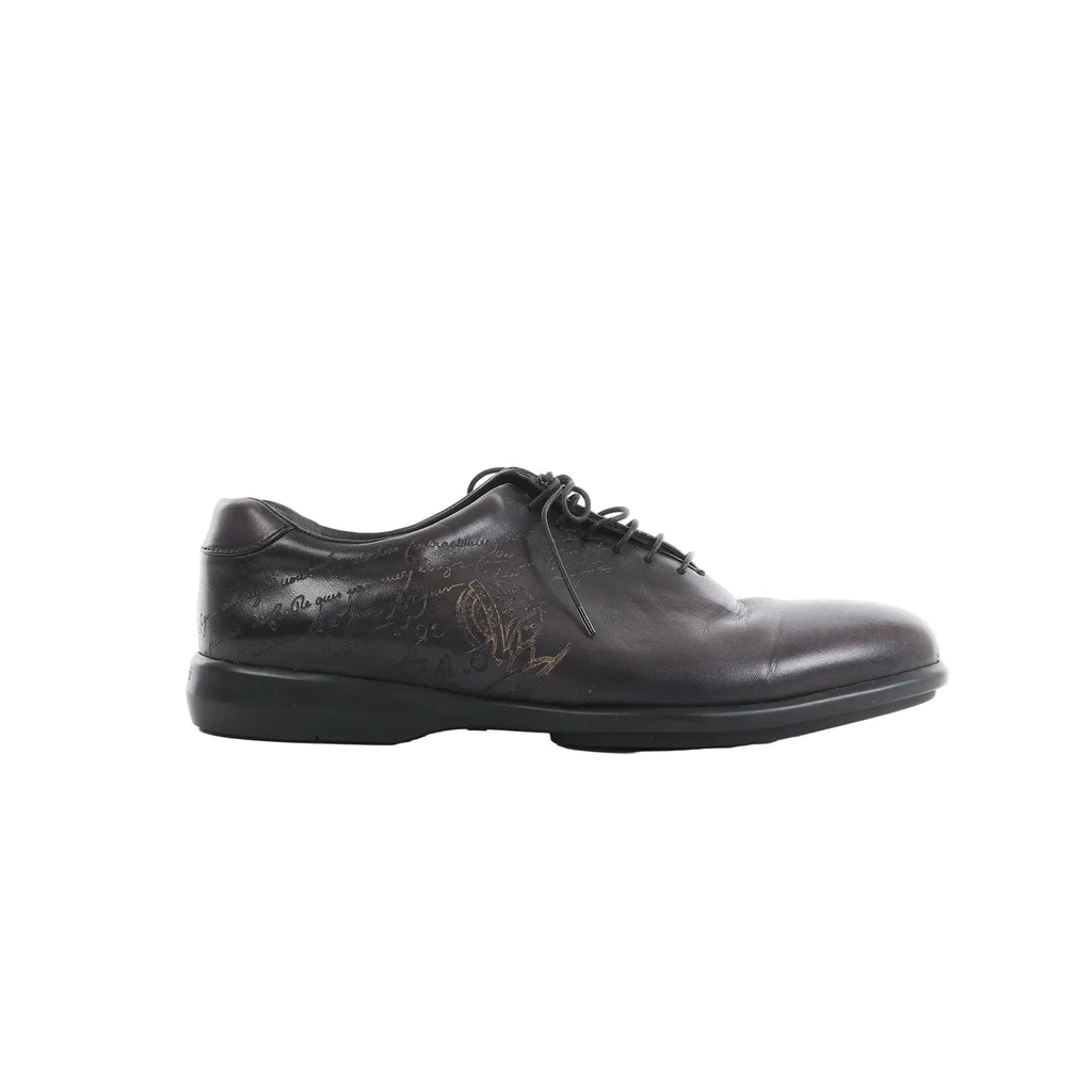 Berluti black leather lace-up shoe with calligraphy detailing on the side and low-profile black sole on white background