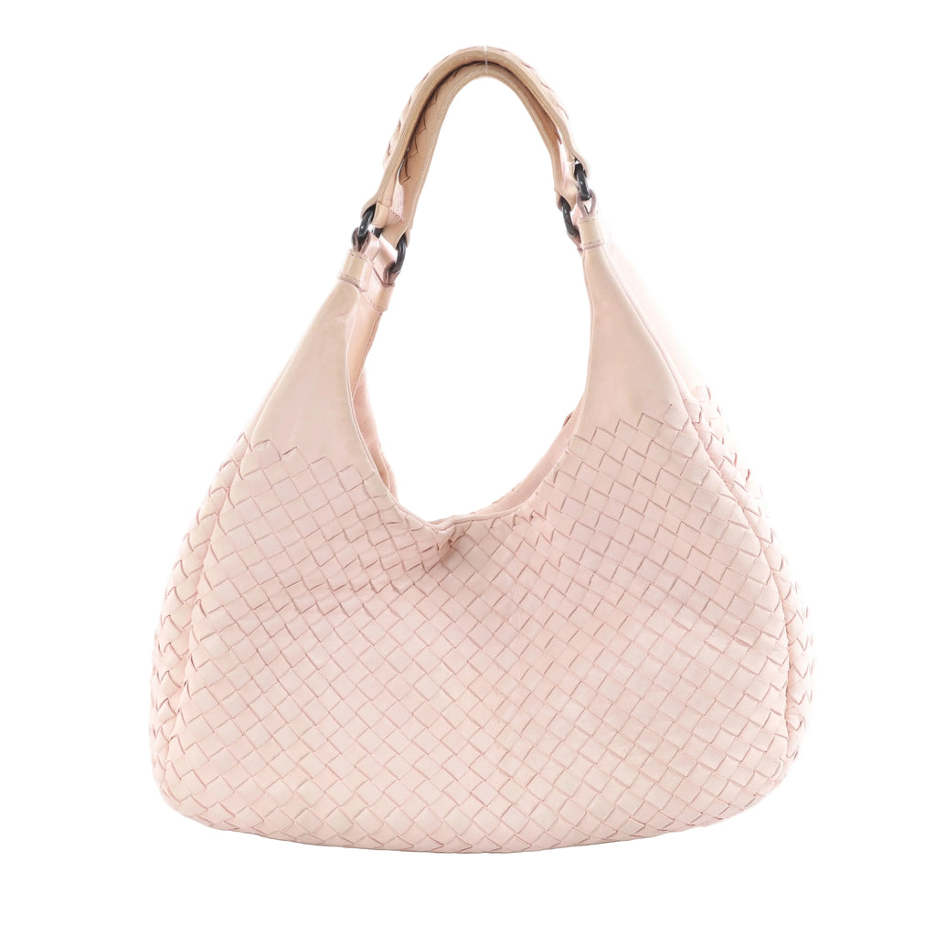Pink Bottega Veneta Campana Intrecciato leather shoulder bag with woven body, curved hobo shape and dark metal handle rings on a white background.