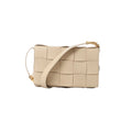 Beige woven leather crossbody bag with wide strap and gold-tone hardware on white background.