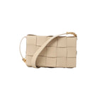 Beige woven leather crossbody bag with wide strap and gold-tone hardware on white background.