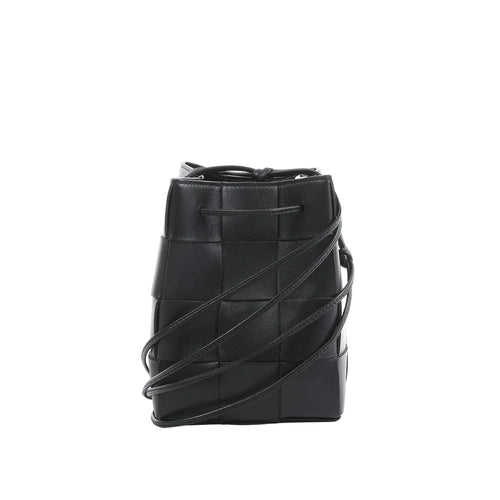 Bottega Veneta Cassette mini bucket bag in black maxi intrecciato woven leather with drawstring top and thin crossbody strap on a white background.