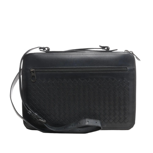 Black Bottega Veneta Intrecciato leather crossbody bag with a woven front panel, top zipper closure, horizontal front zip pocket, and adjustable strap, shown on a white background.