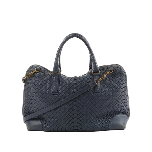Bottega Veneta navy blue Intrecciato woven leather handbag with top handles, detachable shoulder strap, and gold-tone hardware on white background