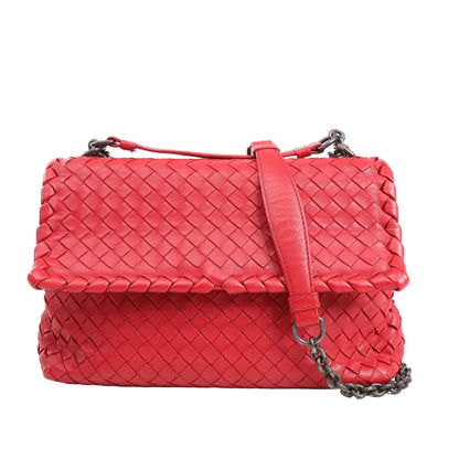 Bottega Veneta Intrecciato shoulder bag in vibrant red woven leather, featuring a flap closure, leather strap with gunmetal chain detail, displayed on a white background.