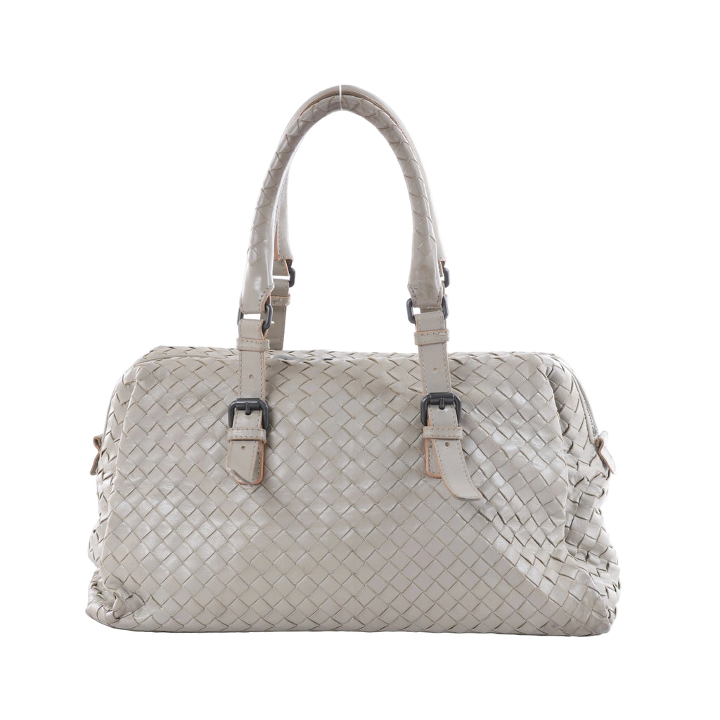 Light gray Bottega Veneta Boston handbag in Intrecciato woven leather with dual top handles, buckle details and dark metal hardware on a white background.