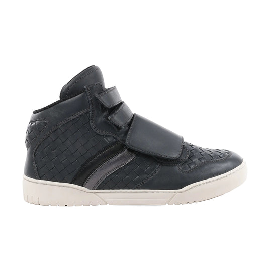 Side view of a navy blue Bottega Veneta Intrecciato leather high-top sneaker in size 43 EU, showcasing woven leather panels, dual velcro straps, glossy accent stripes, and a white rubber sole on a white background.