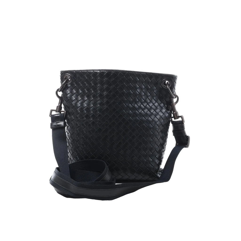 Bottega Veneta Intrecciato crossbody messenger bag in black woven leather with an adjustable shoulder strap, black hardware and bucket-style silhouette on a white background.
