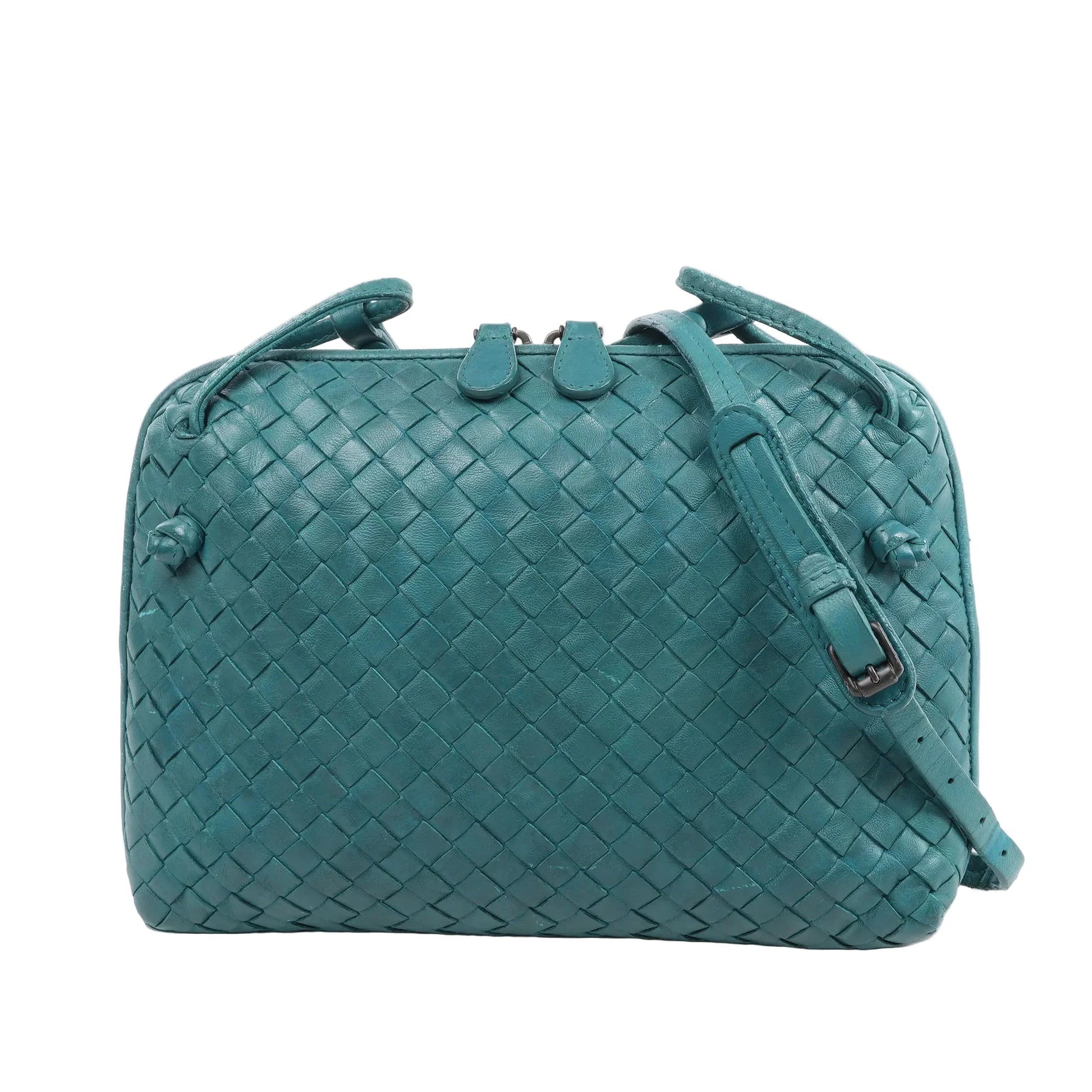 Bottega Veneta Nodini crossbody bag in green Intrecciato woven leather, featuring an adjustable shoulder strap, double zip closure, and compact rectangular shape, displayed against a white background.