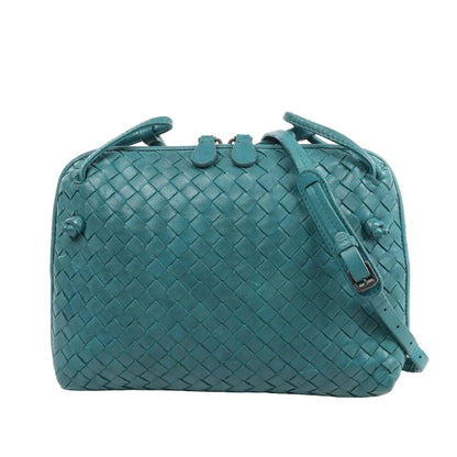 Bottega Veneta Nodini crossbody bag in green Intrecciato woven leather, featuring an adjustable shoulder strap, double zip closure, and compact rectangular shape, displayed against a white background.
