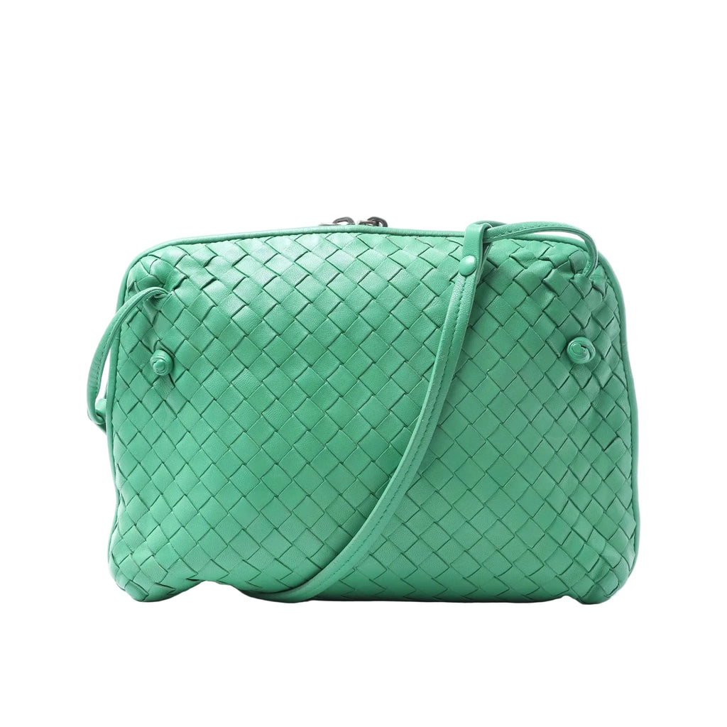 Front view of a green Bottega Veneta Intrecciato woven leather crossbody bag with a slim shoulder strap and knotted side details on a white background.
