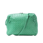 Front view of a green Bottega Veneta Intrecciato woven leather crossbody bag with a slim shoulder strap and knotted side details on a white background.