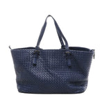 Navy blue Bottega Veneta Intrecciato woven leather shoulder tote bag with two long top handles featuring small buckle details, shown on a white background.
