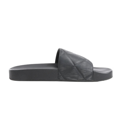 Bottega Veneta Intrecciato Rubber BV Flat Slides in black, size 40 EU, featuring a molded rubber footbed and wide strap with embossed geometric weave pattern, displayed in side profile against a white background.