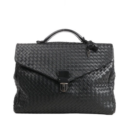 Front view of a Bottega Veneta handbag in black Intrecciato woven leather, featuring a structured top handle, flap closure with lock detail, and attached key.