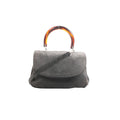 Bottega Veneta gray suede handbag with tortoiseshell-effect top handle, flap front, and detachable shoulder strap, front view on white background.