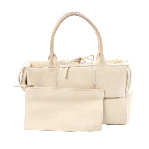 Bottega Veneta Arco Maxi Intrecciato beige leather and shearling handbag with top handles and matching zip pouch on white background.