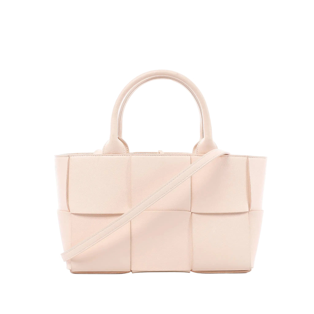 Bottega Veneta Arco handbag in pale pink Maxi Intrecciato woven leather with rounded top handles and slim shoulder strap on white background.