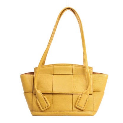 Bottega Veneta Mini Arco handbag in vibrant yellow leather featuring the signature maxi intrecciato weave, structured shape, and dual top handles.