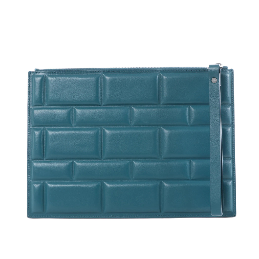 Bottega Veneta Blocs blue leather clutch bag with padded brick-effect panels, top zip closure and slim wrist strap on a white background.