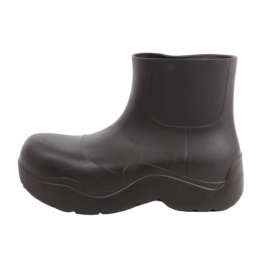 Side view of a brown Bottega Veneta Paddles rubber rain boot in size 40 EU, showcasing a minimalist ankle-high design with a curved sculptural shape and thick treaded sole on a white background.