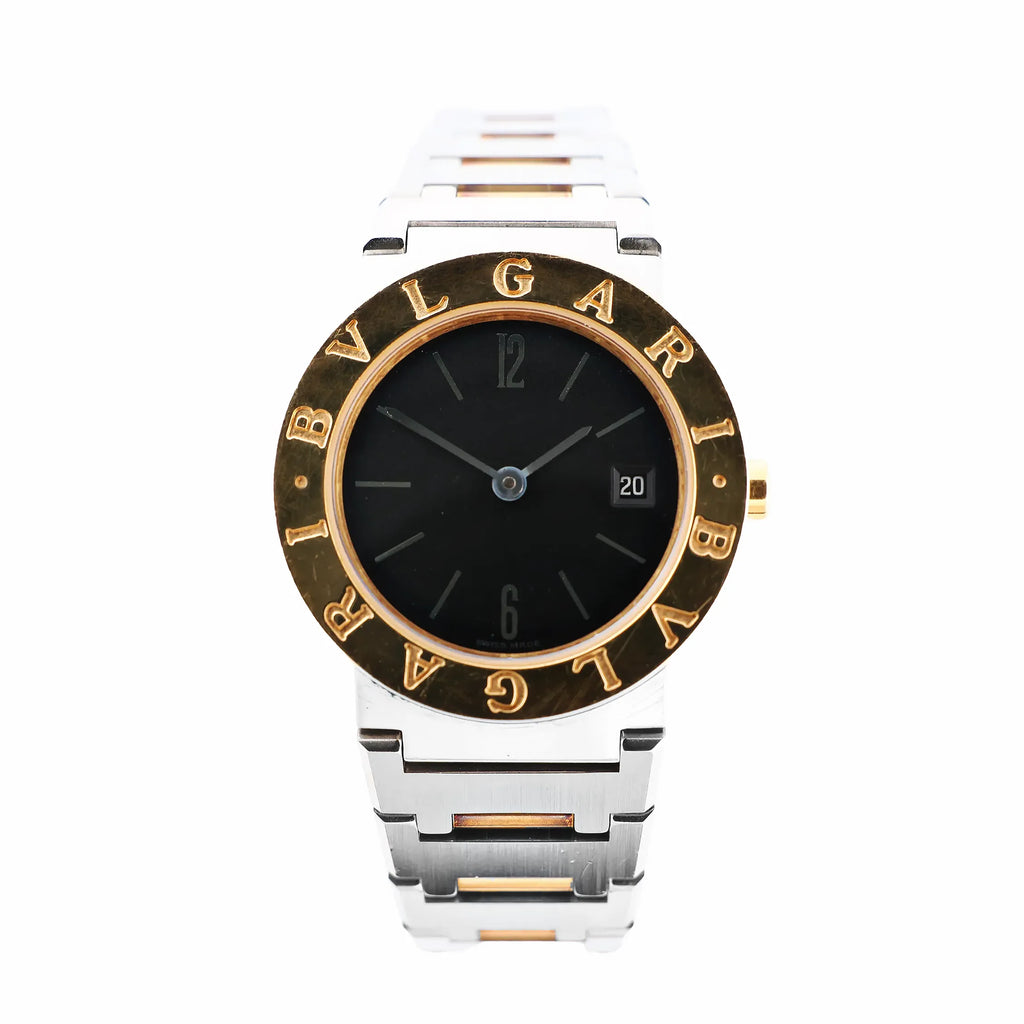 Close-up of a Bvlgari BB26SGD watch featuring a black dial, date display at 3 o’clock, yellow gold bezel engraved with “BVLGARI,” and a two-tone stainless steel and gold bracelet.