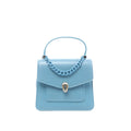 BVLGARI Serpenti Forever handbag in light blue leather with top handle, blue chain detail, flap front pocket, and silver Serpenti snakehead clasp, front view on white background.