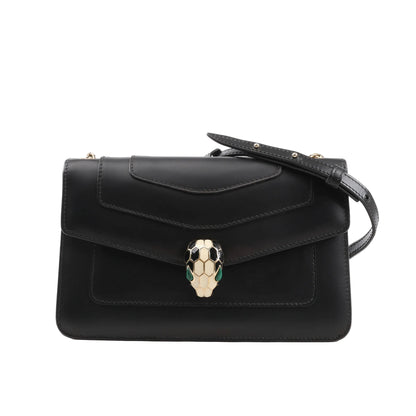 BVLGARI Serpenti Forever chain shoulder bag in black calf leather, featuring a structured silhouette with flap closure, signature enamel Serpenti head clasp in black, white, and green, and a partially visible gold-tone chain strap, set against a white background.