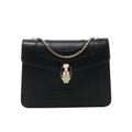 Black Bvlgari Serpenti Forever leather shoulder bag with gold-tone chain strap and signature snake-head clasp with green accents.