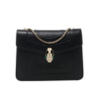 Black Bvlgari Serpenti Forever leather shoulder bag with gold-tone chain strap and signature snake-head clasp with green accents.