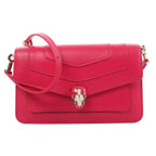 BVLGARI Serpenti Forever pink leather crossbody bag with flap front, enamel snakehead clasp, and adjustable shoulder strap on a white background.