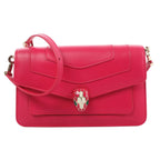 BVLGARI Serpenti Forever pink leather crossbody bag with flap front, enamel snakehead clasp, and adjustable shoulder strap on a white background.