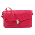 BVLGARI Serpenti Forever pink leather crossbody bag with flap front, enamel snakehead clasp, and adjustable shoulder strap on a white background.