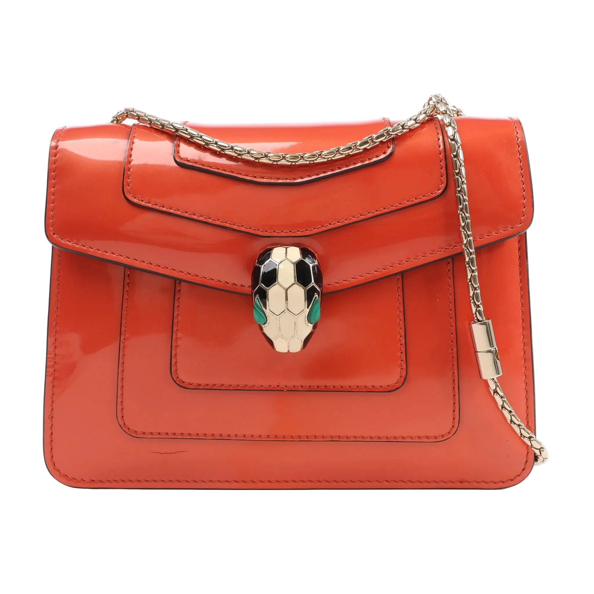 BVLGARI Serpenti Forever shoulder bag in glossy orange patent leather, adorned with a gold-tone chain strap and signature snakehead clasp with black, white, and green enamel detailing, shown against a white background.