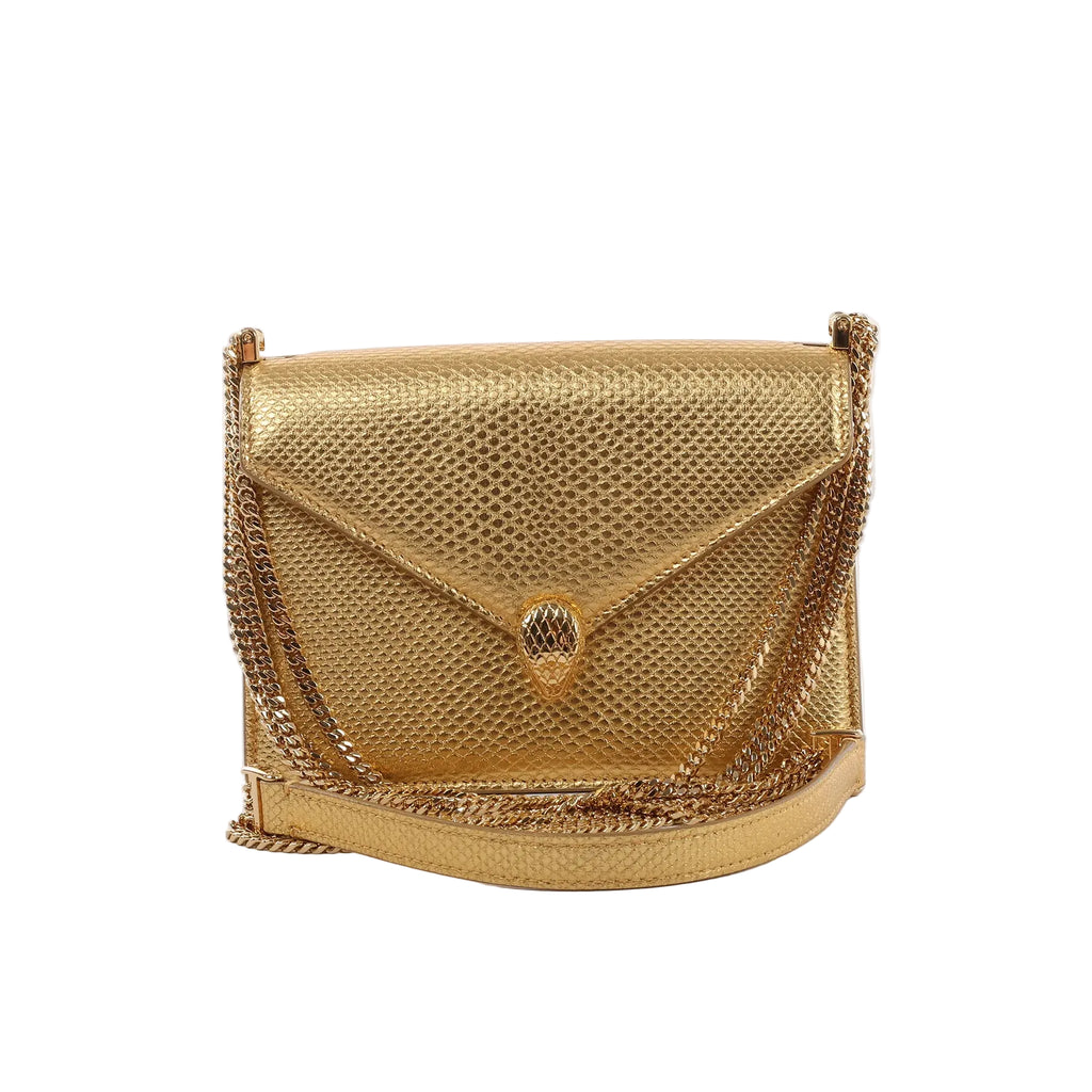 BVLGARI Serpenti gold textured leather crossbody bag with flap closure, snakehead clasp, and gold chain strap on a white background.