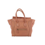 Pink CELINE Luggage Micro Shopper handbag in pebbled leather with rolled top handles, winged sides, front zip pocket and gold-tone hardware.