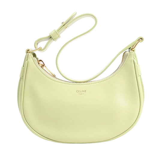 Front view of the CELINE Ava Leather Shoulder Bag in pastel green, showcasing its curved crescent silhouette, smooth leather finish, adjustable strap, and gold-tone zipper and logo, against a white background.