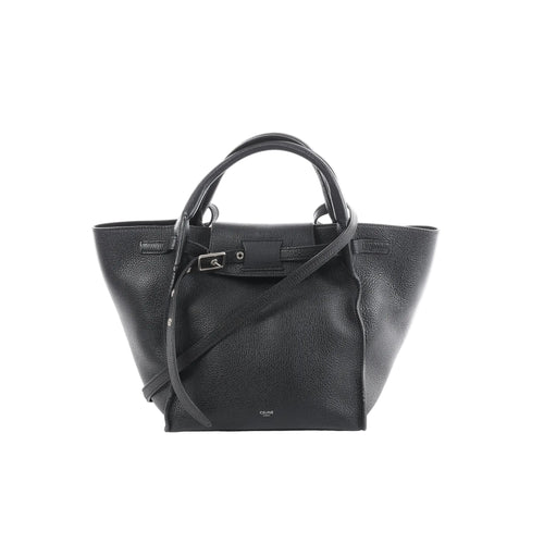Céline Big Bag Small black grained leather tote with top handles, long shoulder strap, and front buckle strap detail, front view on white background.