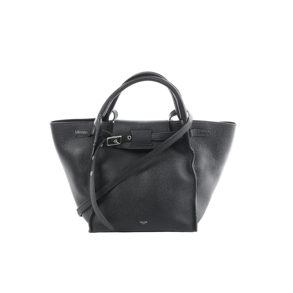 Céline Big Bag Small black grained leather tote with top handles, long shoulder strap, and front buckle strap detail, front view on white background.