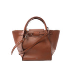 CELINE Big Bag Small handbag in smooth brown leather with structured silhouette, front belt detail, top handle, and detachable shoulder strap on a light gray background.