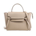 CELINE Belt Bag Micro 2Way Handbag in beige grained leather, showcasing a structured design with a top handle, knotted front belt detail, winged sides, and a detachable shoulder strap, displayed against a white background.